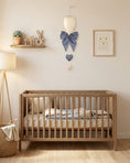 Load image into Gallery viewer, Nursery room with wooden crib, decorative items, and a light-colored wall.